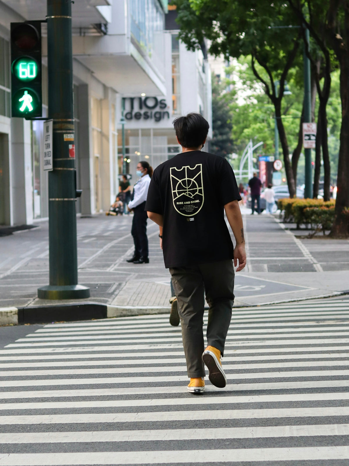 man in black t-shirt and brown pants walking on pedestrian lane during daytime